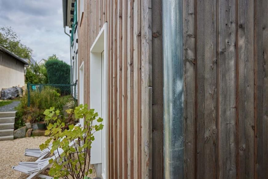 Ein Haus mit einer Holzverkleidung und einem Metallrohr an der Seite.