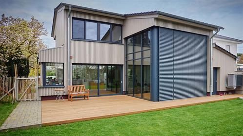 Ein großes Haus mit vielen Fenstern und einer Holzterrasse.