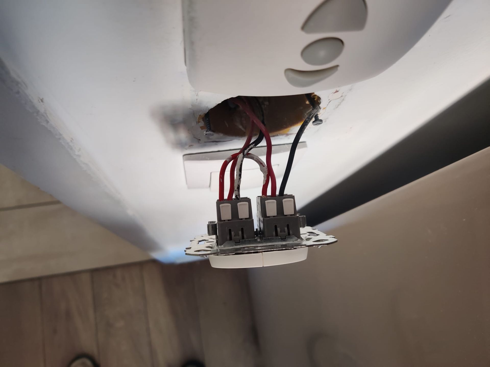 Câblage électrique avec des fils rouges et noirs connectés à deux connecteurs gris, monté sur une surface blanche.