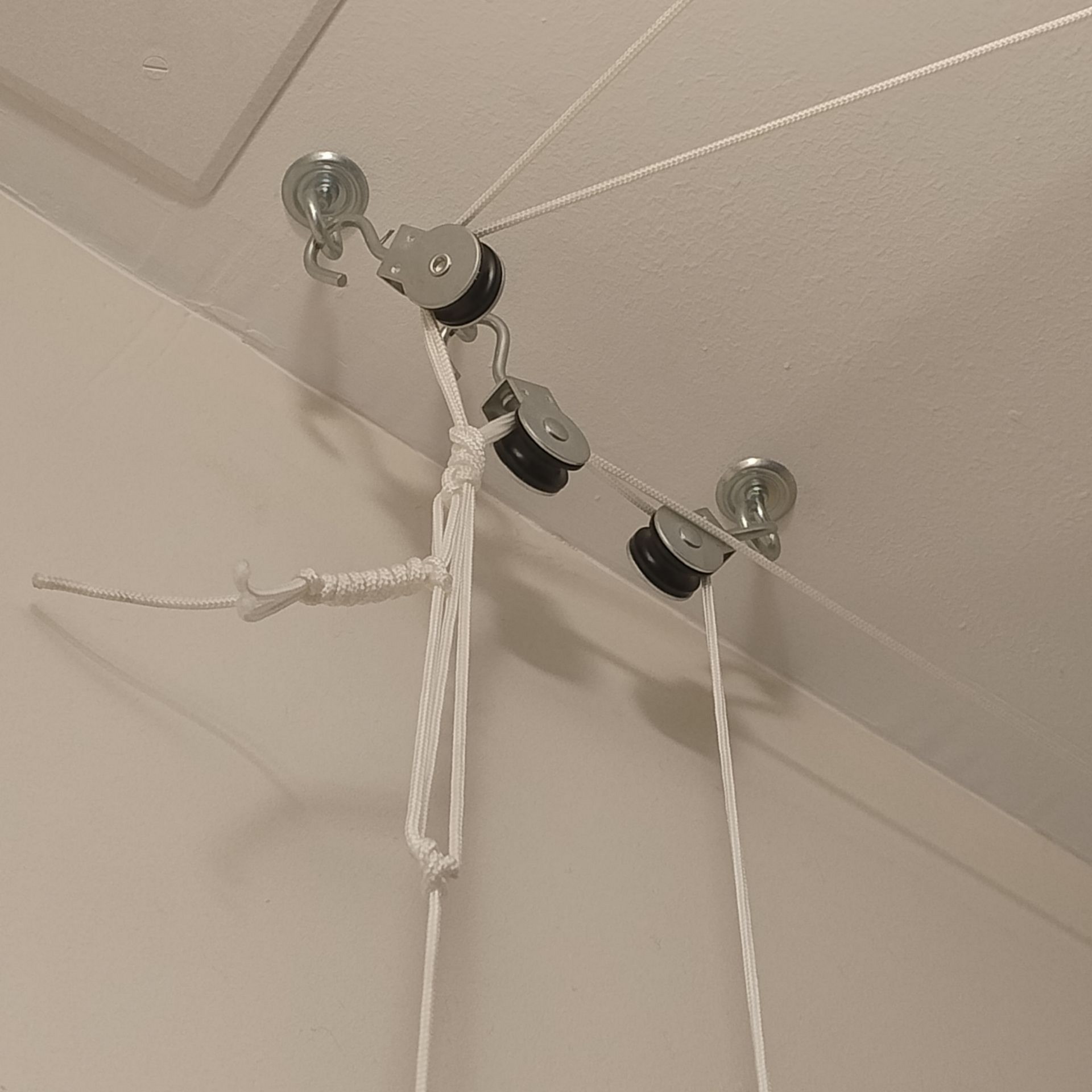 Corde blanche et poulies fixées à un plafond blanc.