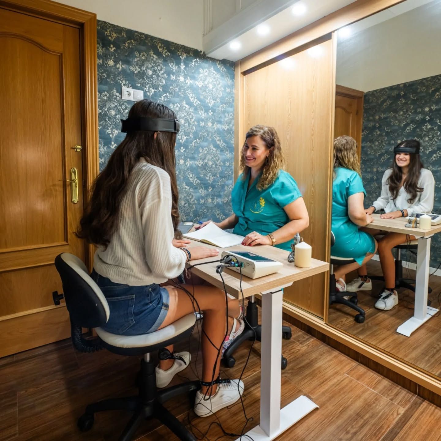 Una mujer con una blusa verde azulado consulta con un paciente 