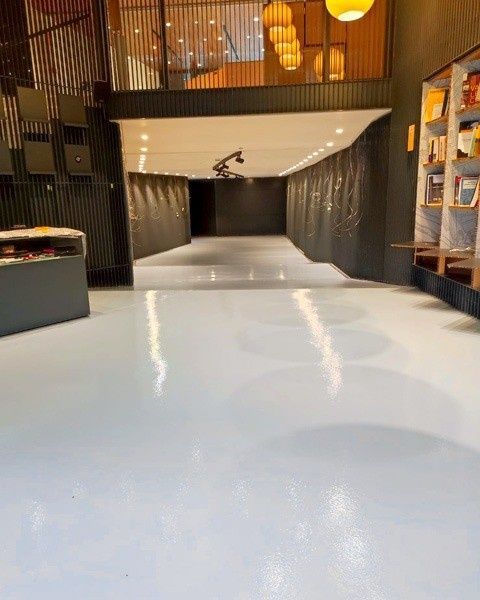 Un suelo pulido de color claro se extiende a lo largo de un pasillo oscuro