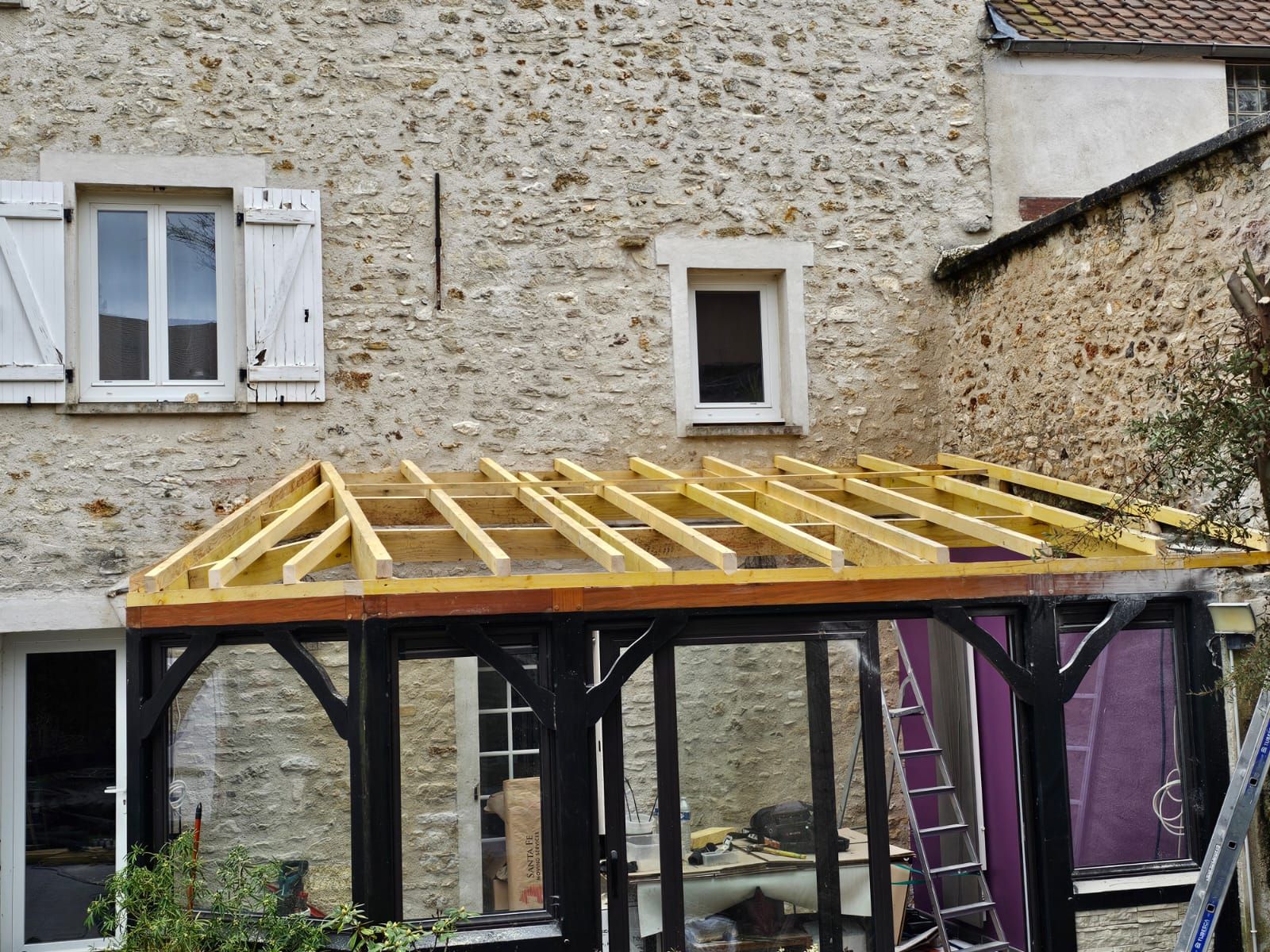 Abri de porte en cours de réalisation avec charpente apparente