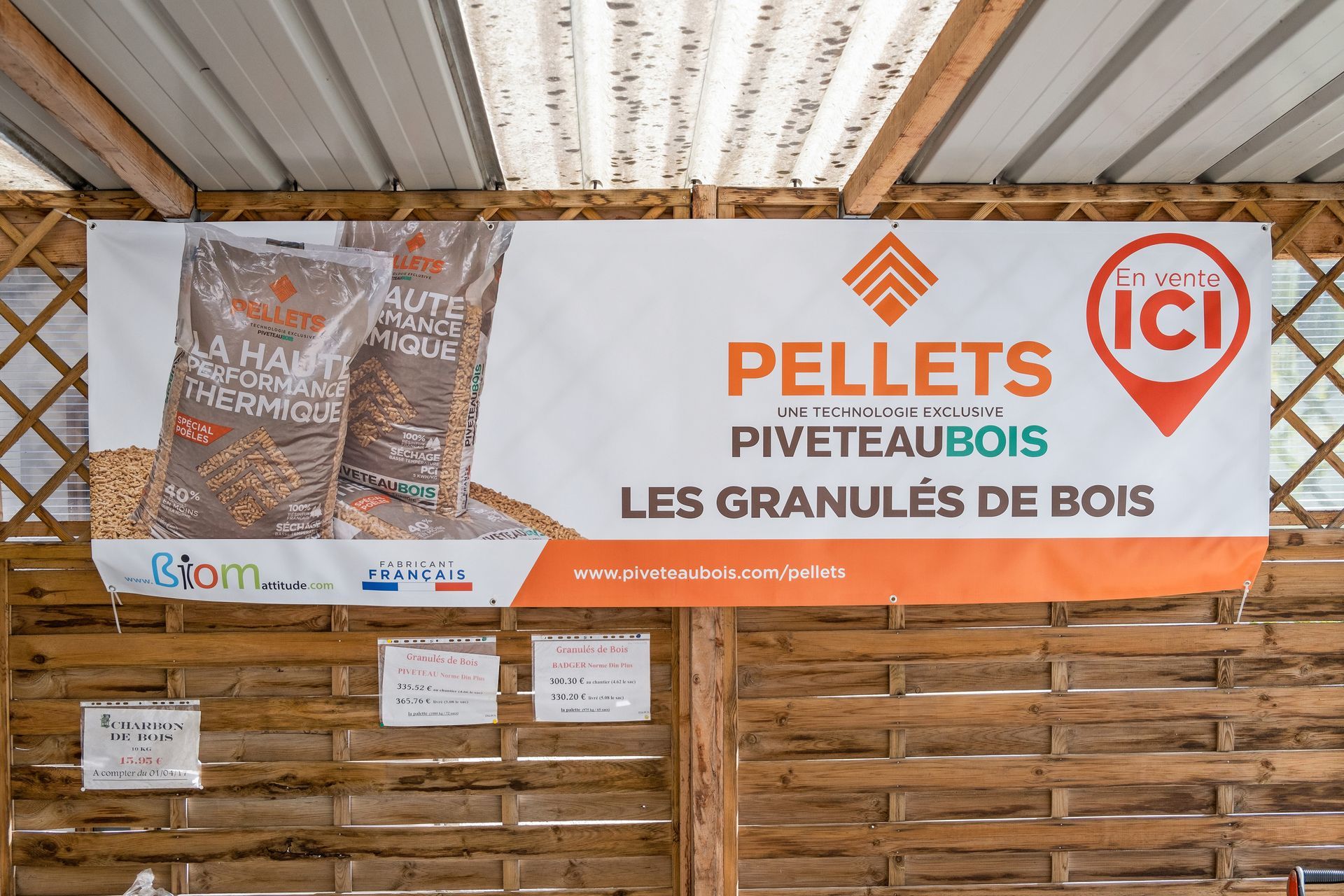 Une pancarte publicitaire pour les granulés de bois PiveteauBois est accrochée à un mur en treillis de bois.