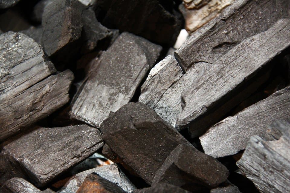 Gros plan sur un tas de briquettes de charbon de bois gris foncé et rugueuses.