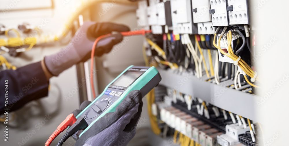 Un électricien teste un tableau électrique avec un multimètre.