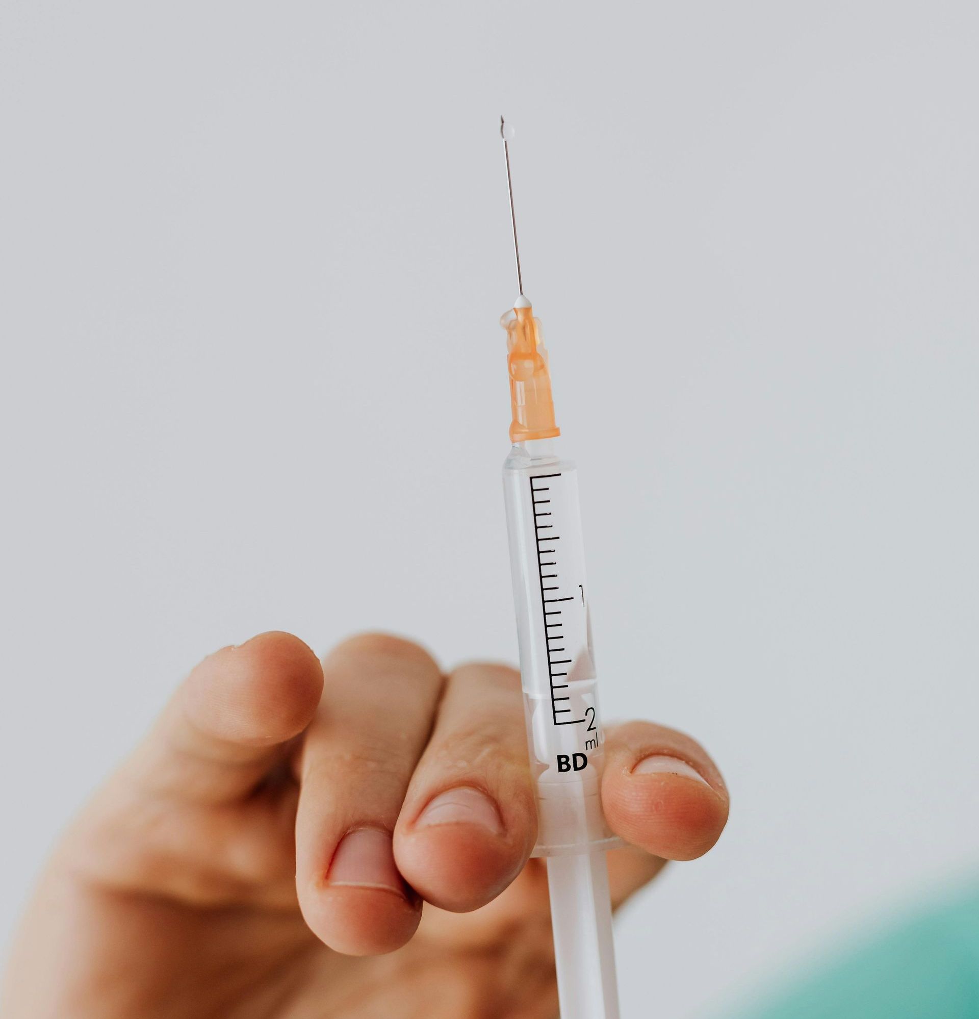 Eine Person hält eine Spritze in der Hand.