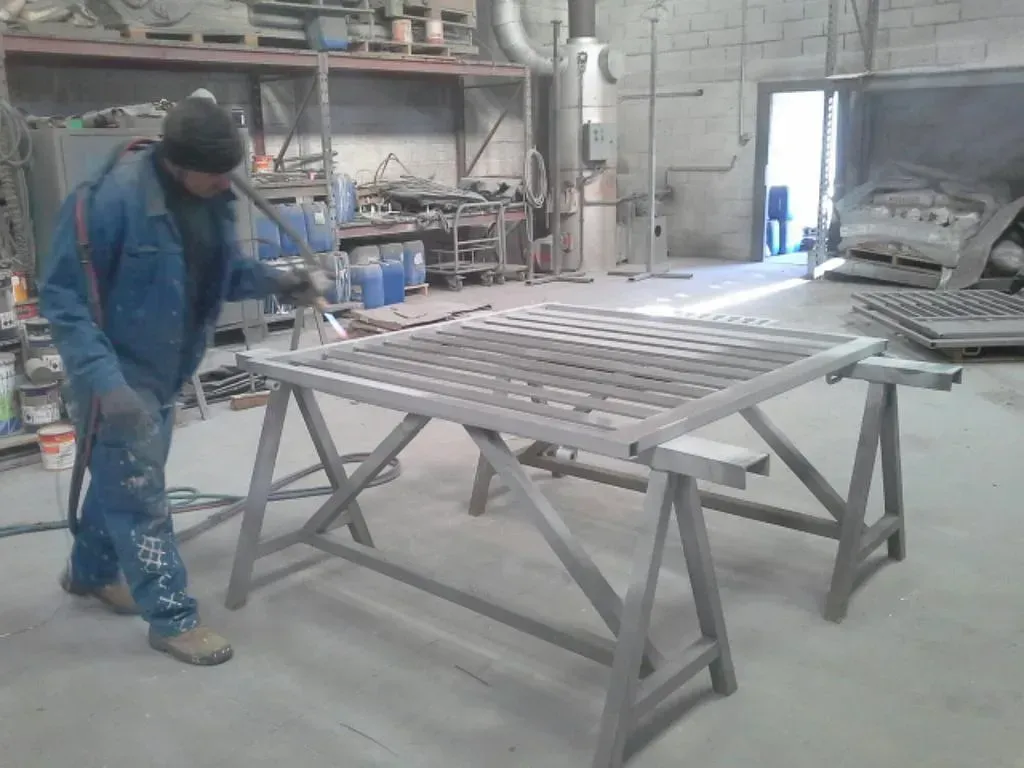 Ouvrier sablant une grille dans l’atelier