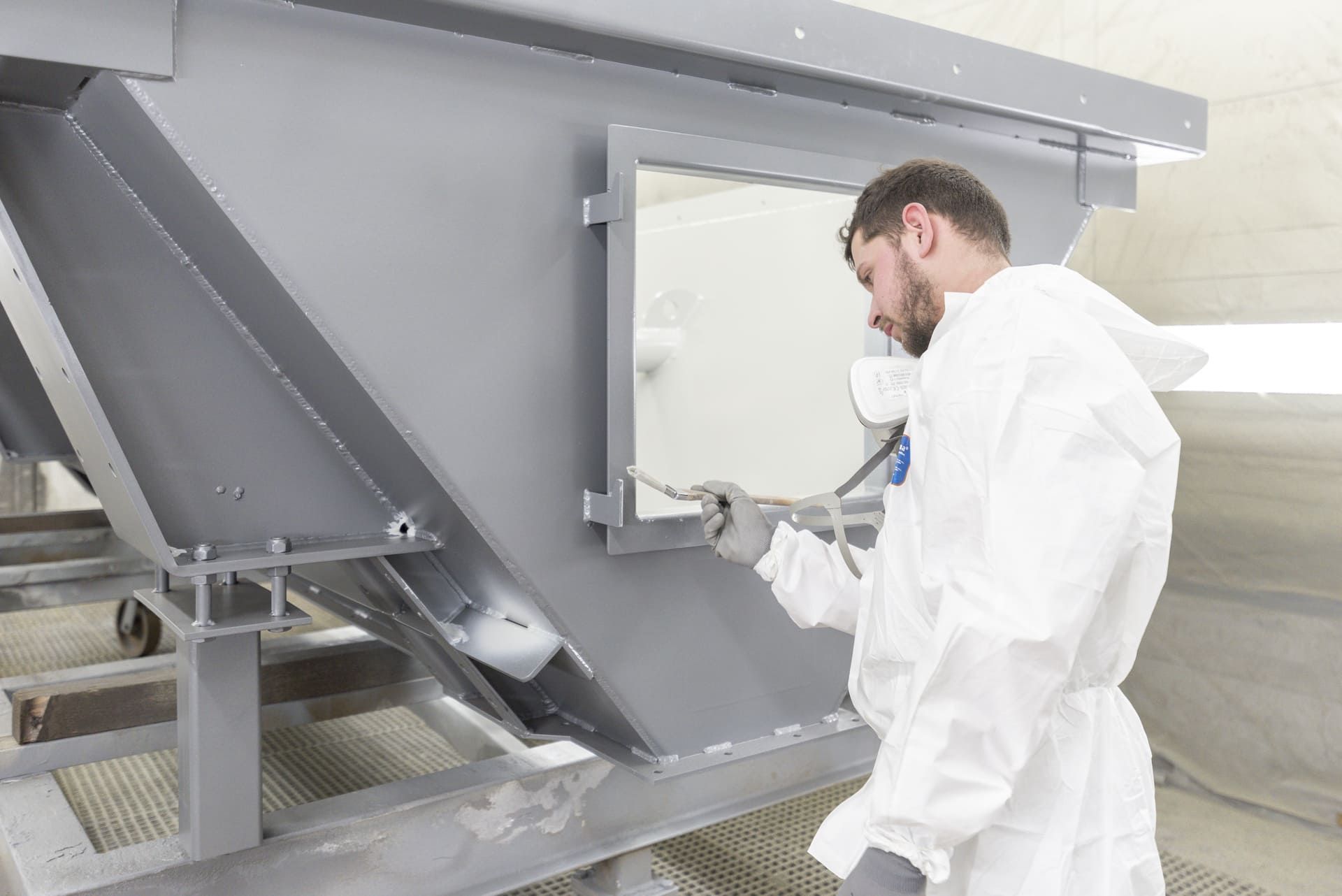 Ouvrier appliquant de la peinture sur une pièce métallique