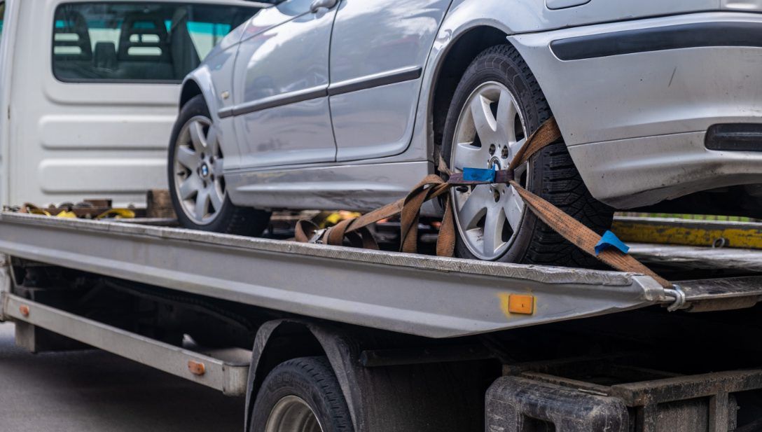 Auto plateado asegurado en una grúa de plataforma. Las correas sujetan las ruedas.