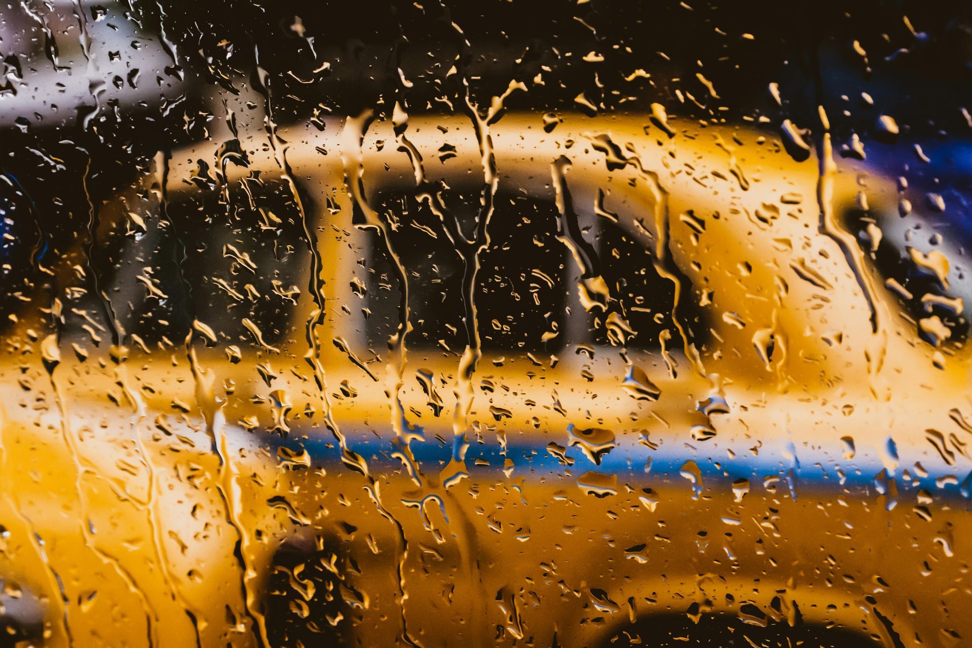 Las gotas de lluvia en una ventana oscurecen un taxi amarillo.