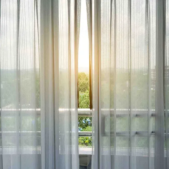 El sol brilla a través de las cortinas de una ventana.