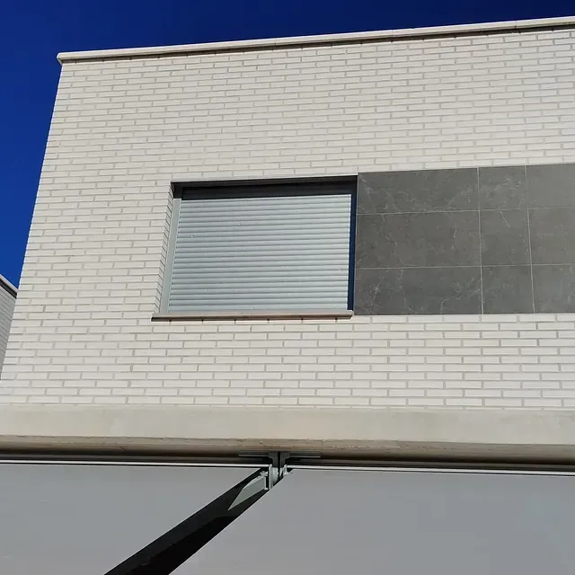Un edificio de ladrillo blanco con una ventana con persiana.