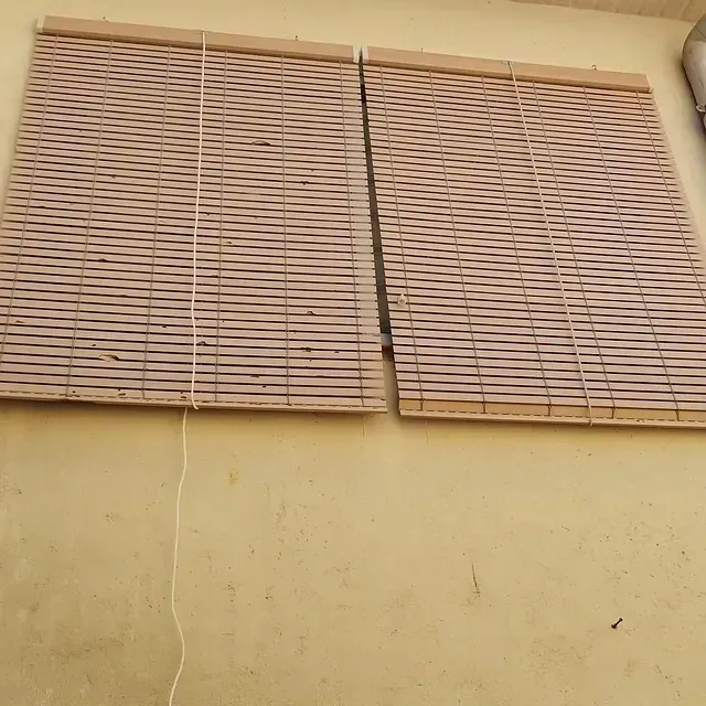 Un par de persianas de bambú en una pared amarilla.