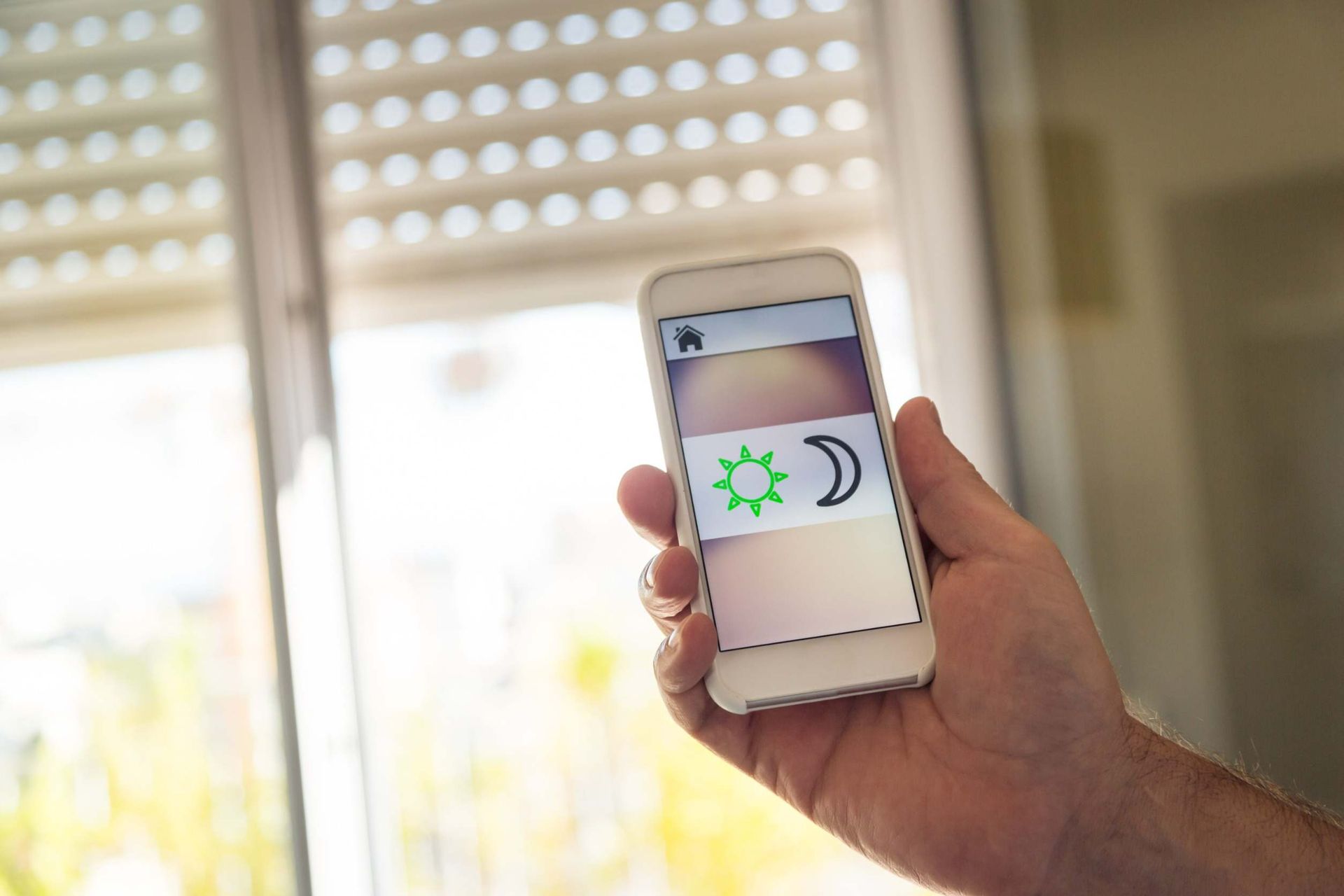 Una persona sostiene un teléfono celular frente a una ventana.