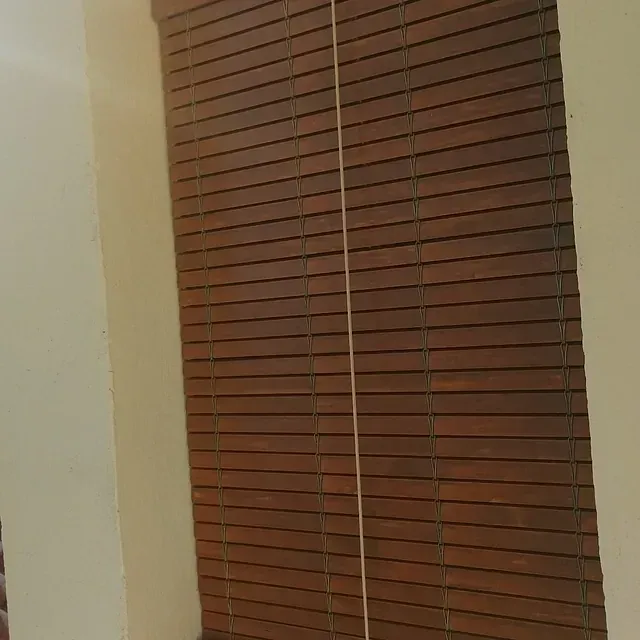 Una persiana de madera está colgada en una ventana de una habitación.