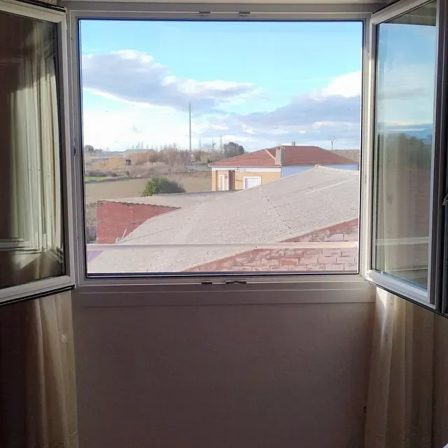 Una habitación con una ventana abierta y vistas a una ciudad.