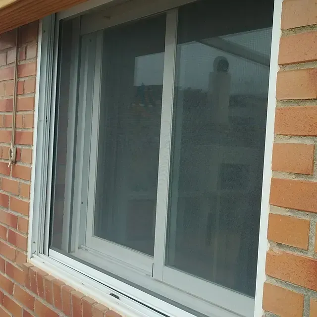 Un edificio de ladrillo con una ventana con mosquitera.