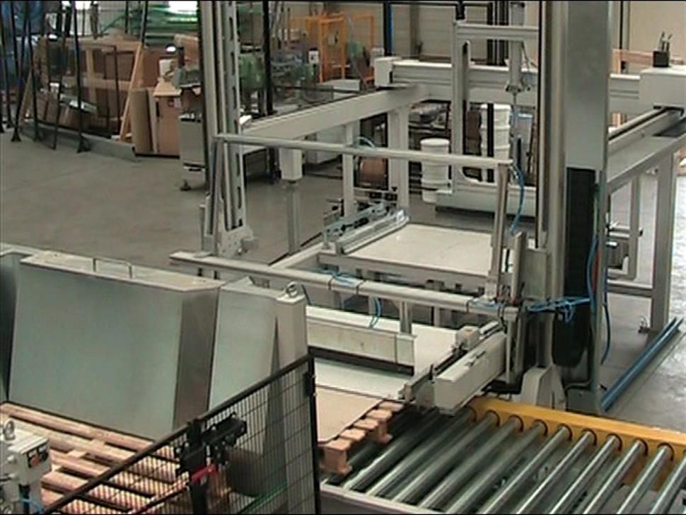 Una macchina sposta delle scatole su un nastro trasportatore in una fabbrica.