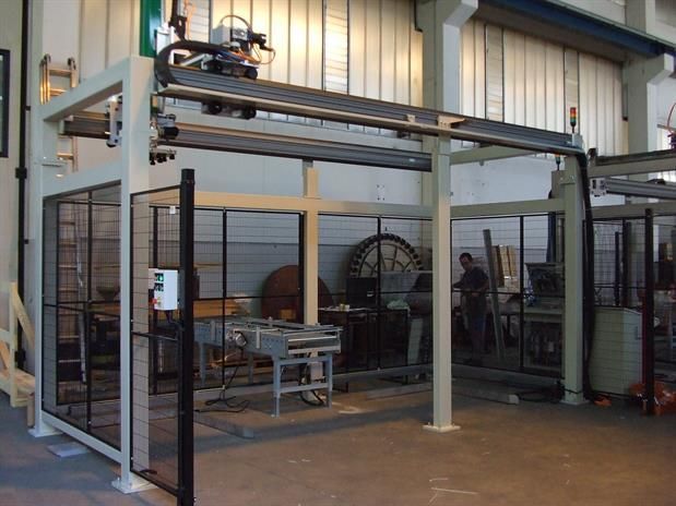 Un uomo sta lavorando a una macchina in una fabbrica dietro una recinzione.