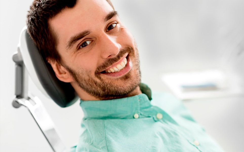 Un hombre sonríe mientras está sentado en una silla dental.