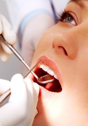 Una mujer se está haciendo examinar los dientes por un dentista.