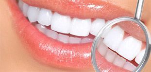 Una mujer se hace examinar los dientes por un dentista con un espejo.