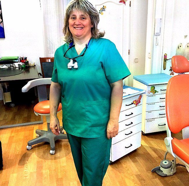 Una mujer con un uniforme verde está de pie en un consultorio dental.