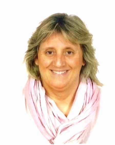 Una mujer que lleva una bufanda rosa sonríe a la cámara.