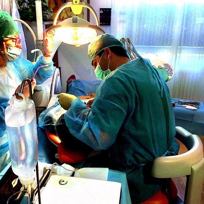 Un hombre con bata quirúrgica está trabajando en un paciente.