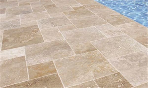 Carreaux de pierre beige bordant un bassin d'eau bleue.