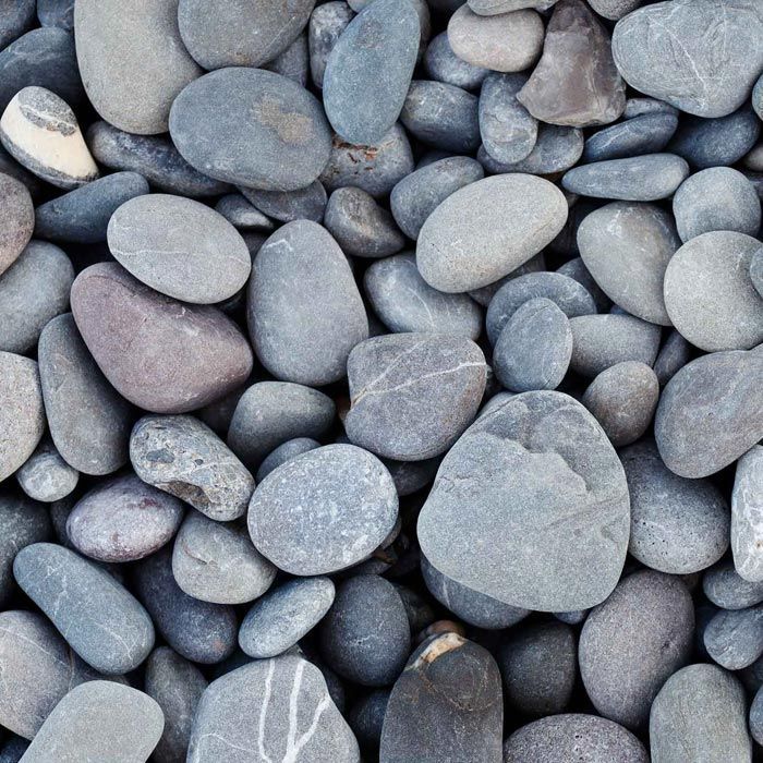 Gros plan de roches de rivière lisses grises et bleues, de différentes tailles et formes.