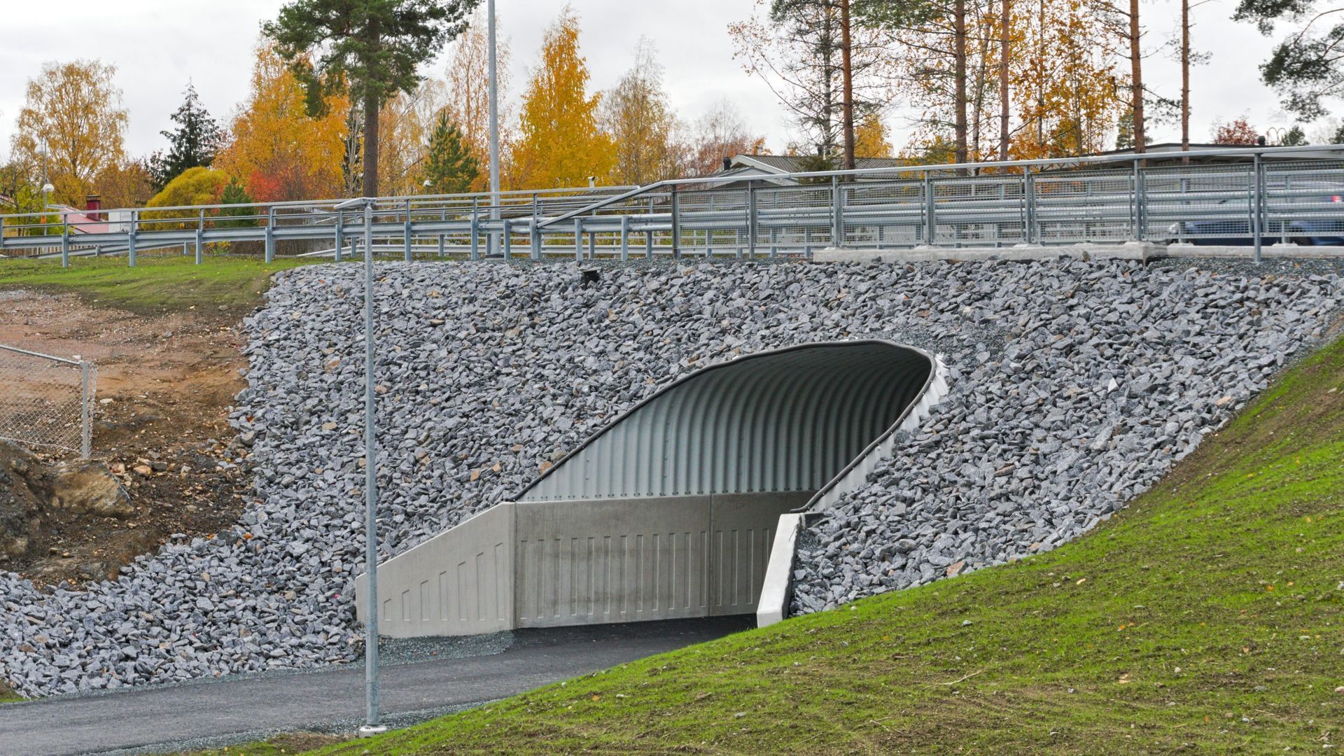 Tunneli sillan alla, jota ympäröivät kivet ja ruoho