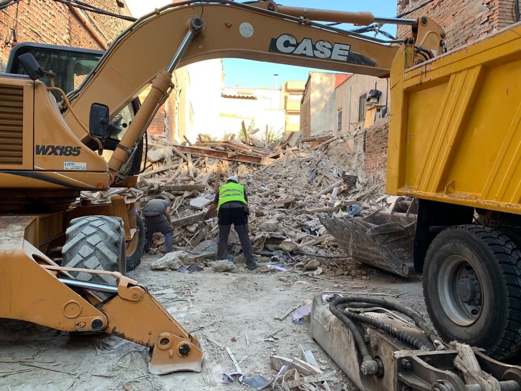 Un hombre está parado frente a una excavadora y un camión volquete.