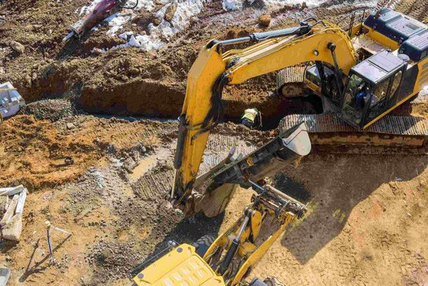 Una excavadora amarilla está cavando un hoyo en la tierra en un sitio de construcción.