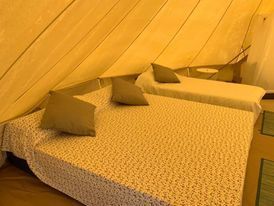 Una tienda de campaña con dos camas y almohadas dentro.