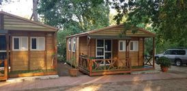 Un par de pequeñas casas de madera con un coche aparcado delante de ellas.