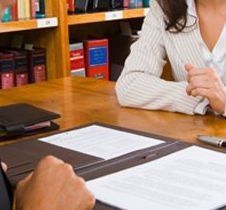 Dos personas sentadas a una mesa revisando documentos en una reunión de oficina.