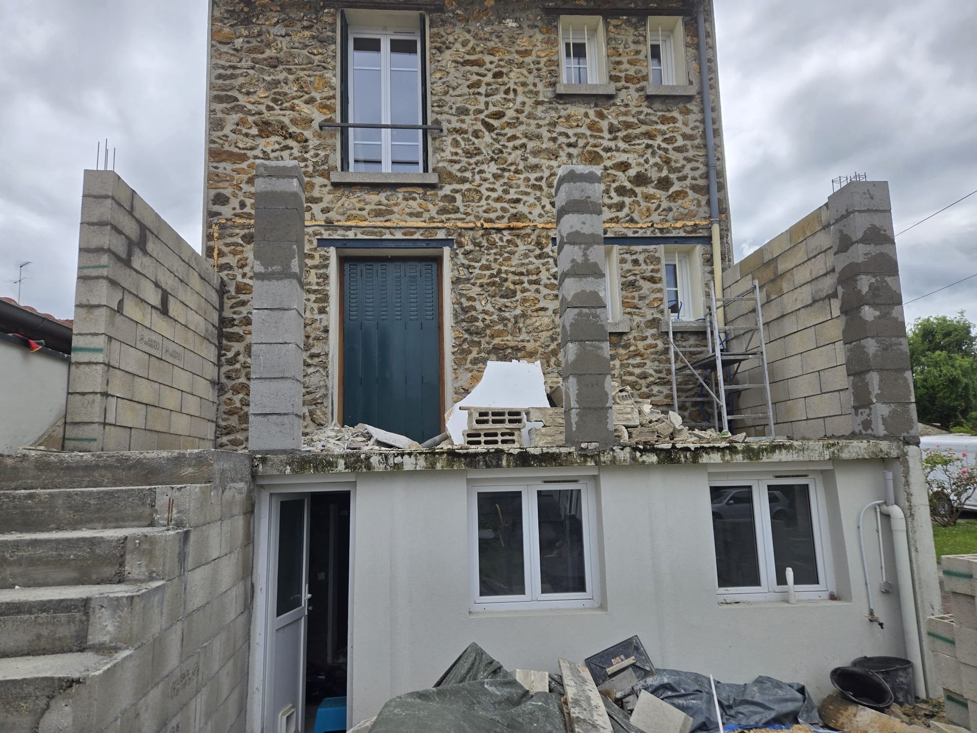 Maison en pierres avec une extension en construction.