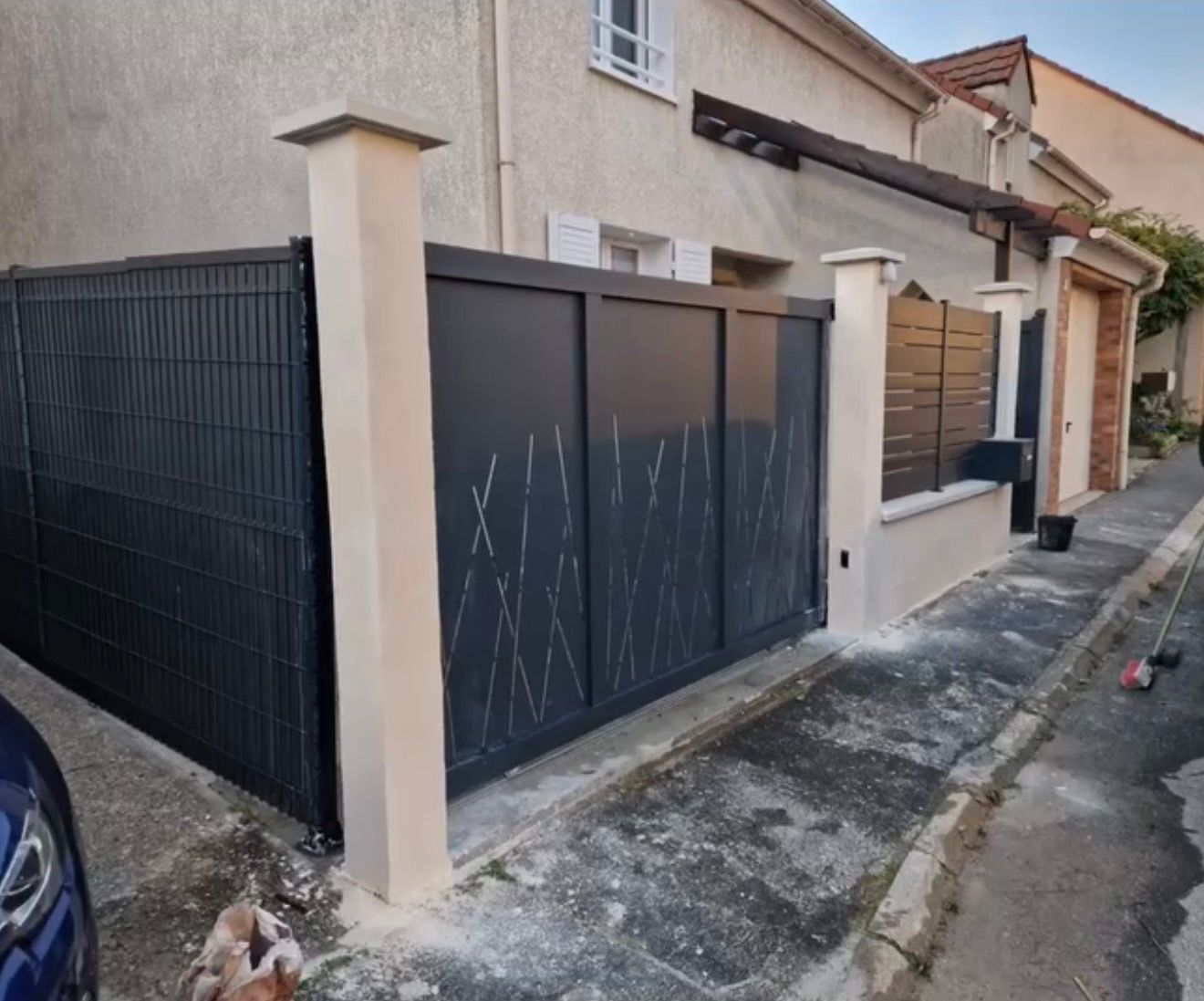 Ruelle résidentielle étroite avec un portail en métal noir.