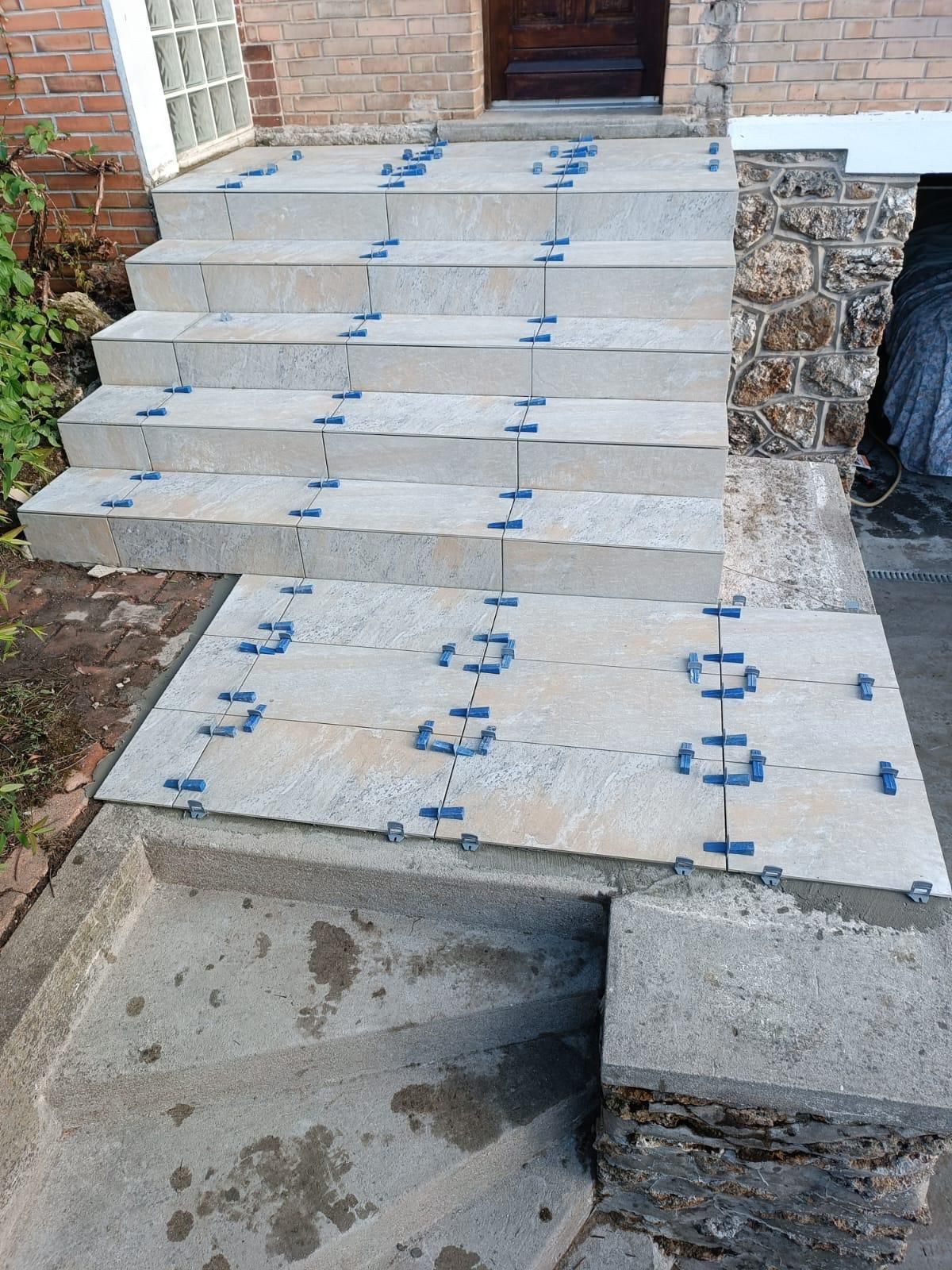 Escaliers en béton en construction avec des entretoises bleues menant à une porte.