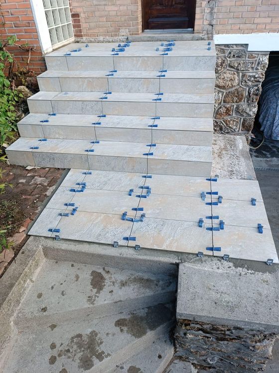 Escaliers en béton en construction avec des entretoises bleues menant à une porte.