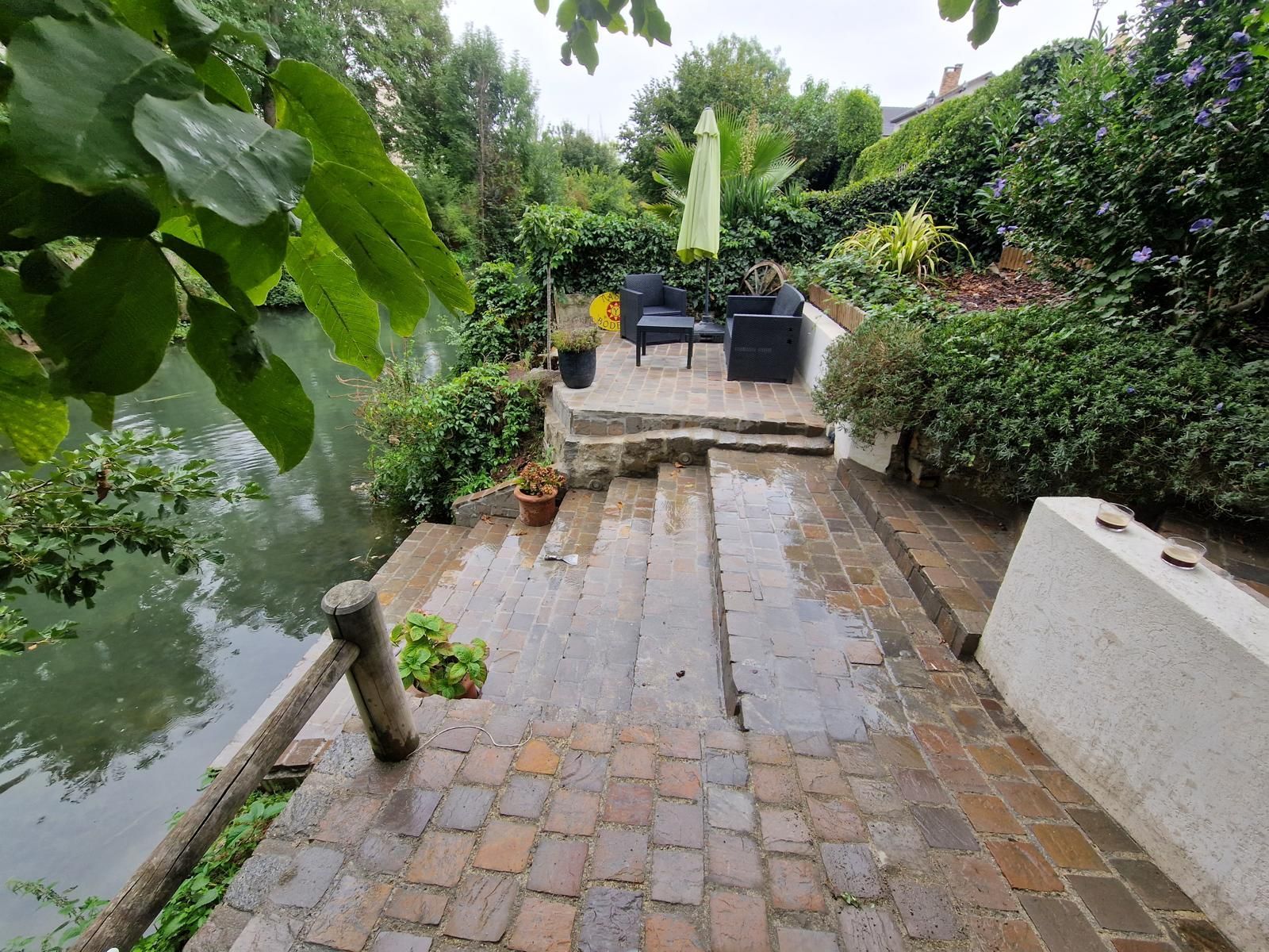 Terrasse et escaliers en pavés au bord d'une rivière.