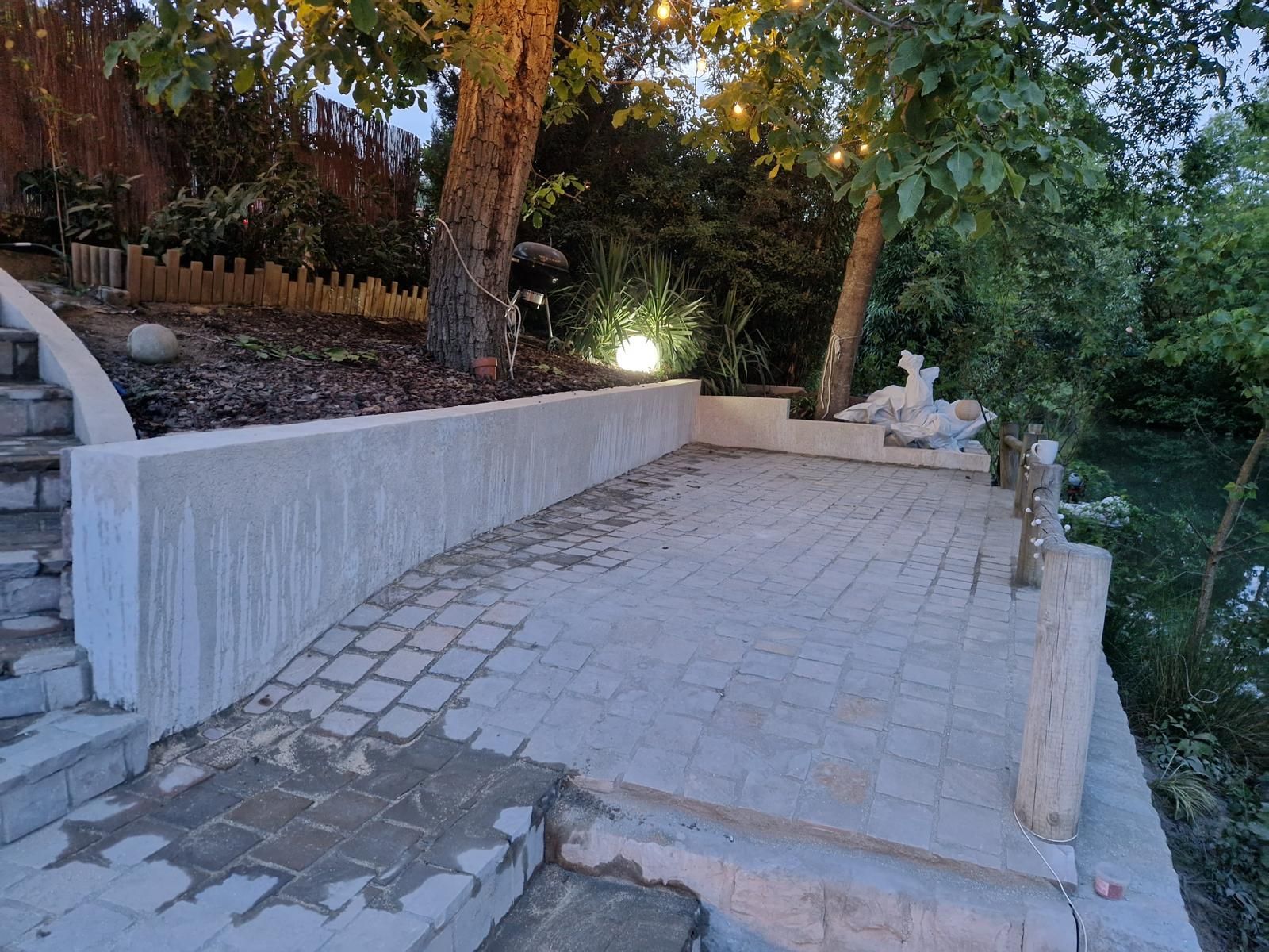 Allée pavée avec des marches et un muret bordé d'arbres et d'un chemin de jardin au crépuscule