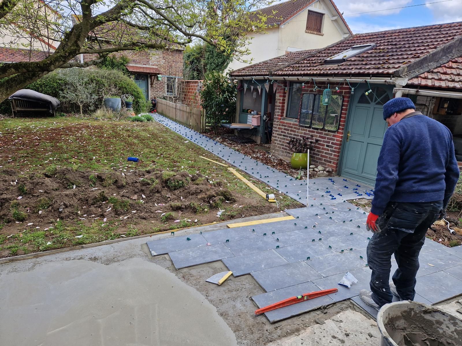 Un ouvrier pose du carrelage extérieur.