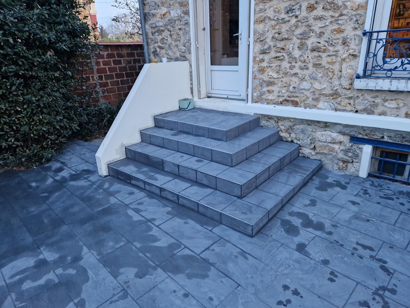 Des marches en pierre mènent à une porte d'entrée blanche.