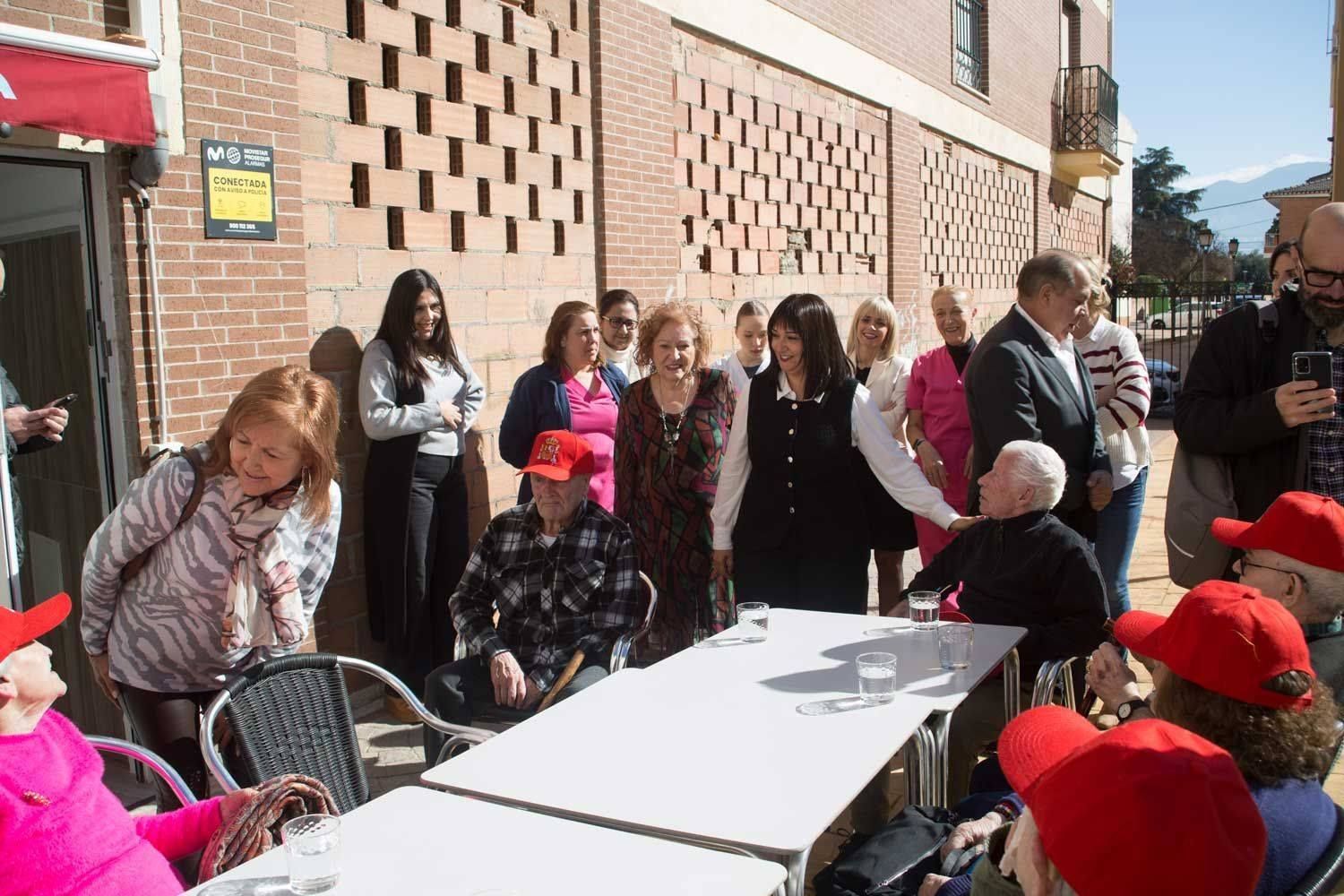 Un grupo de personas están sentadas en mesas afuera de un edificio.
