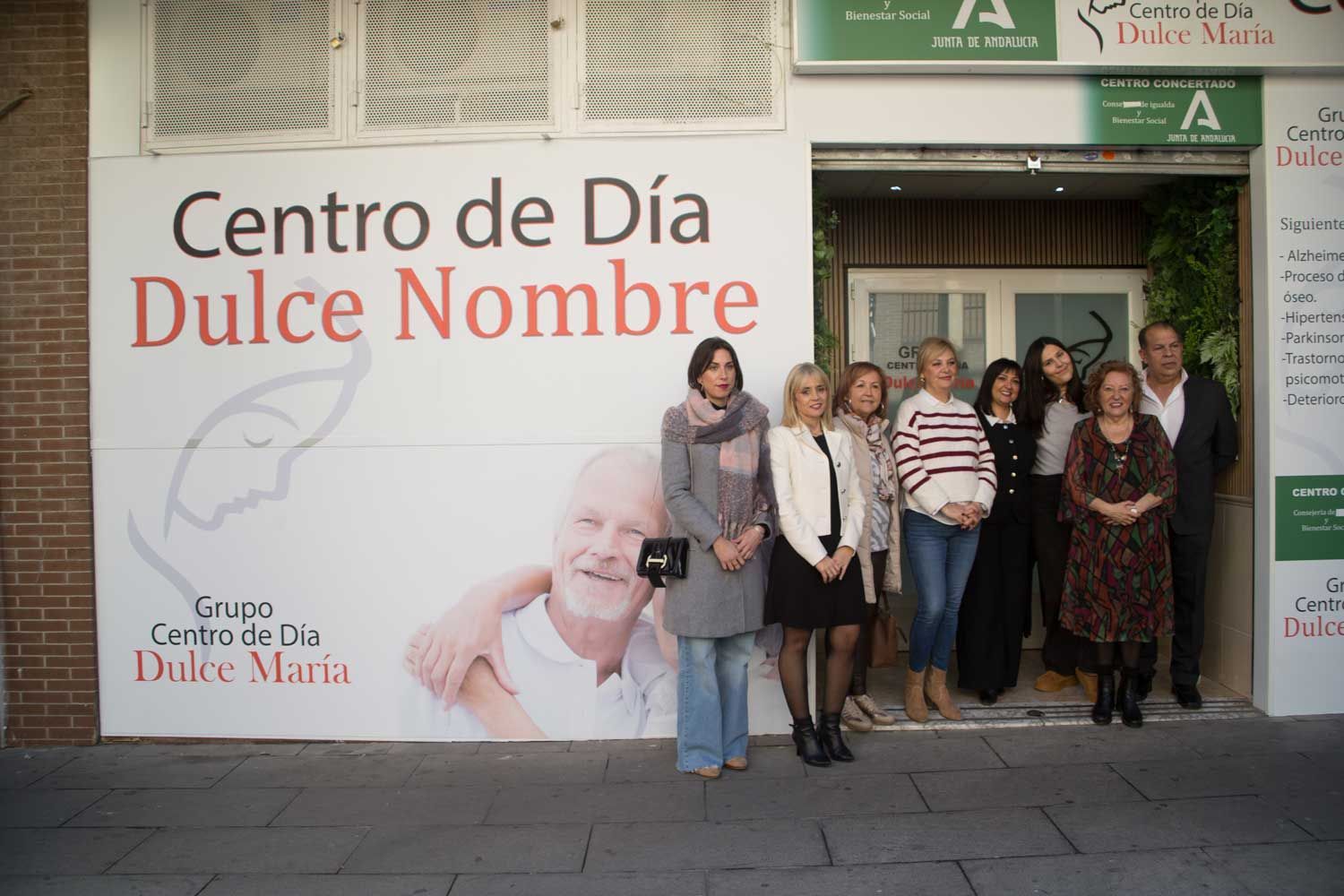 Un grupo de personas de pie frente a un cartel que dice centro de día dulce nombre