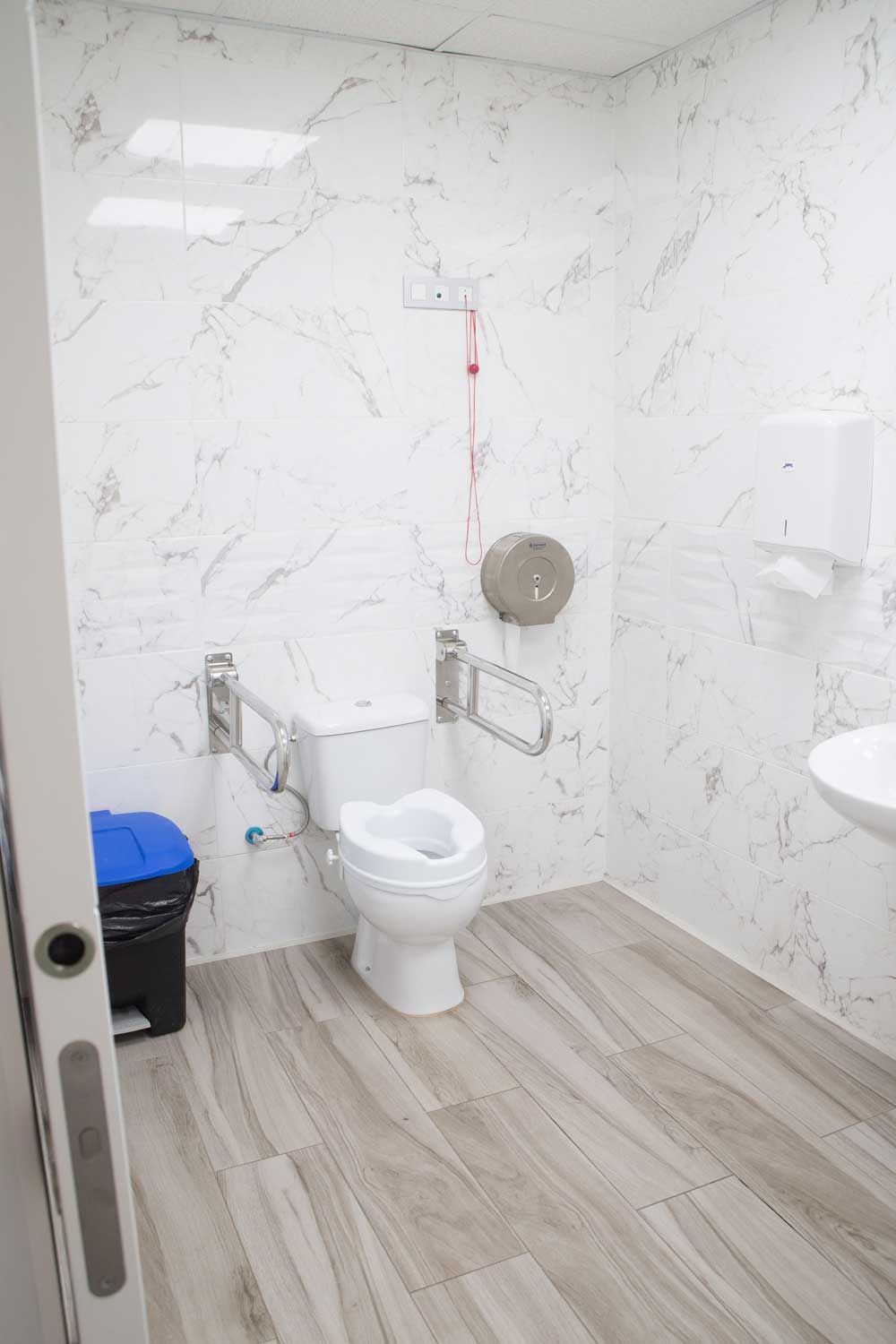 Un baño con inodoro, lavabo y bote de basura.