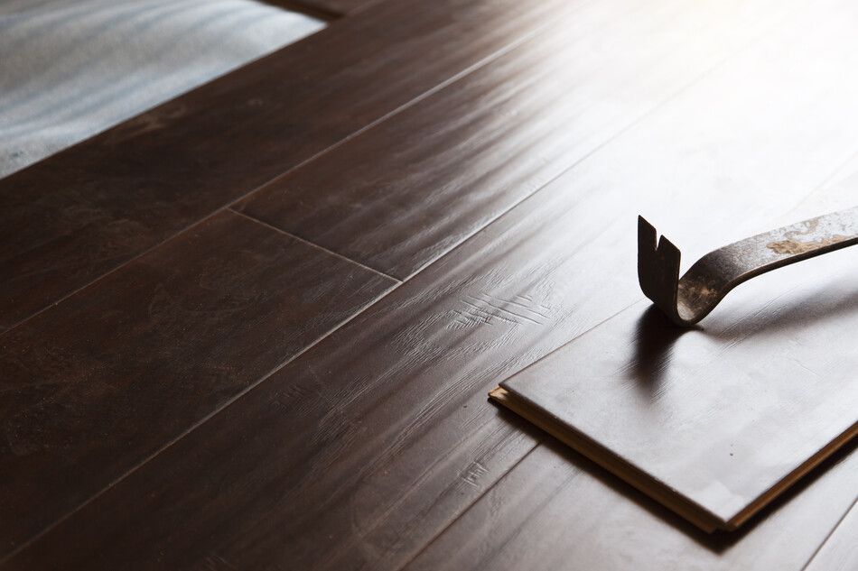 Un martillo está apoyado sobre un trozo de madera en un piso de madera.